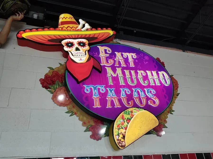 Colorful illuminated Eat Mucho Tacos restaurant sign